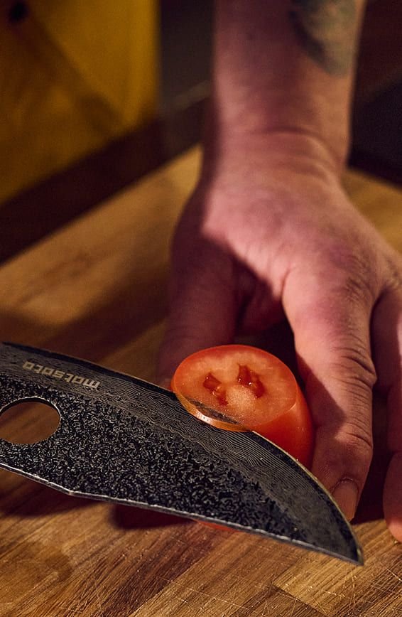 Matsato knife cutting a ripe tomato